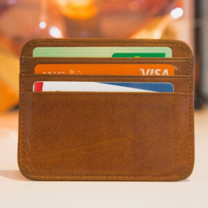 A brown leather card holder with three credit cards in its slots