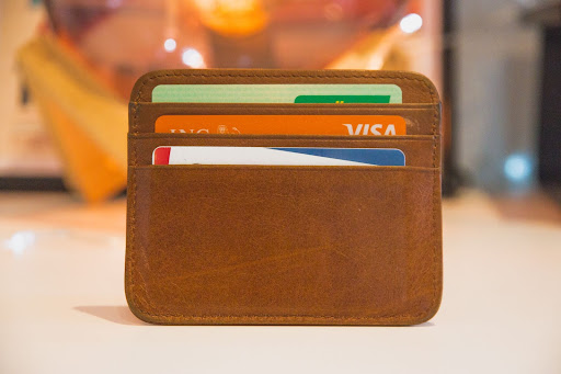 A brown leather card holder with three credit cards in its slots