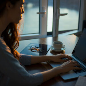 Woman working on her laptop with a cup of coffee on the desk
